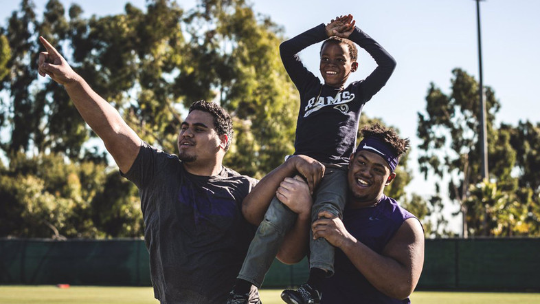 Washington linemen carry a young participant during a YMCA event following practice.